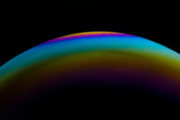 Detail of light in a soap bubble, allusion to the micro universe in a studio with a black background, use of natural and artificial light.
