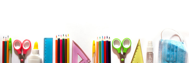 Fototapeta premium Back to school background concept. School supplies and means of prevention of COVID-19 on a white background. Mask and sanitizer. Banner. copyspace