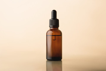 Serum glass bottle with pipette on the beige reflective background. Natural Organic Spa Cosmetic concept. Front view.
