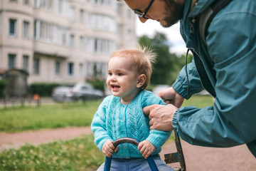 Child swinging on the seesaw walks with his father