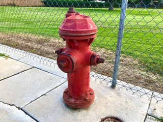 Fototapeta na wymiar Red Fire Hydrant with a fence in the background