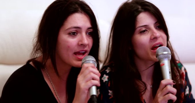 Casual women singing karaoke at home. People holding microphone singing having fun entertainment