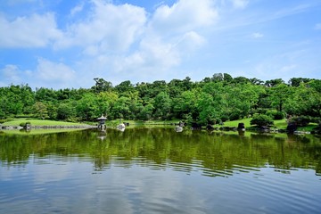 青空バックに新緑に包まれた日本庭園の情景