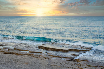 Sunrise on the shore of midterranean sea with dramatic sky.