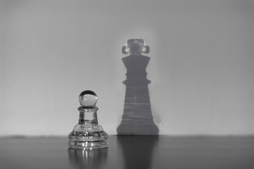 A chess pawn and a shadow of the queen figure - the concept of personal growth and success