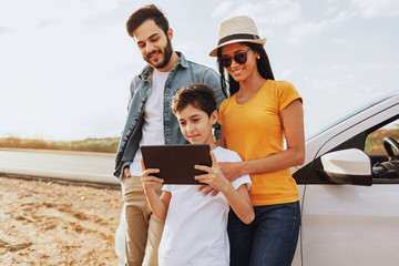 Family road trip. Latin family traveling locally by car. Using map on tablet for navigation