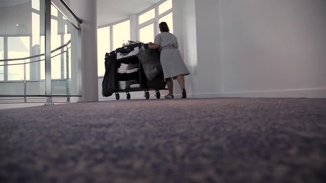 cleaning woman pushing trolley in a hotel corridor