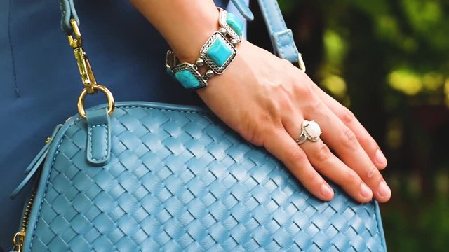 
Turquoise bangle and opal ring In the arms of a woman carrying a bag