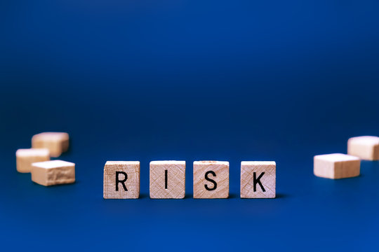 Word - Risk. Square wooden letters on a blue background
