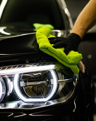 Closeup shot of a man cleaning car headlight with a microfiber cloth