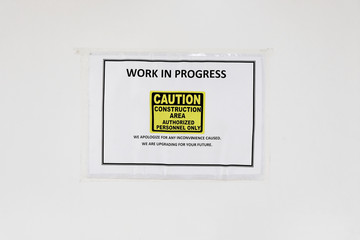 Under construction sign pasted on a boarded up area cautioning the public of maintenance and upgrading works in progress at a section of a building with only authorized personnel allowed entry.