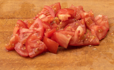 Sliced tomatoes on a wooden background. In the process of cooking salad