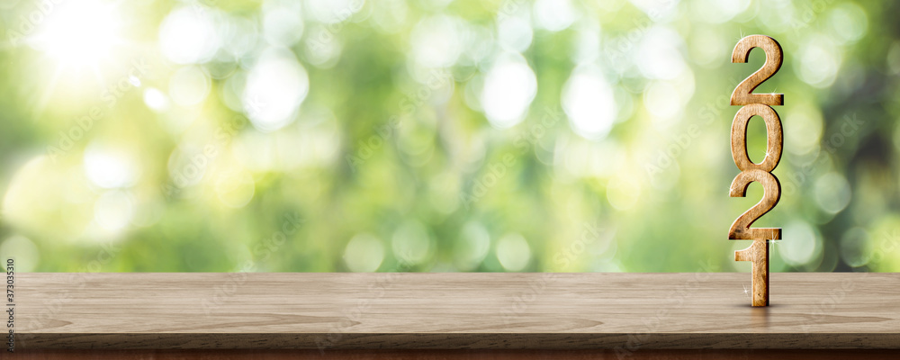 Aufkleber new year 2021 wood number (3d rendering) on wooden table at blur abstract green tree bokeh backgroun