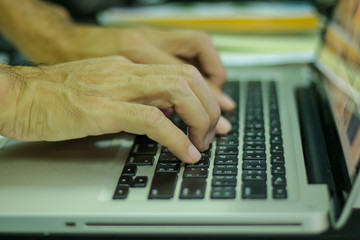 Man hands working on laptop keyboard, closeup shot.