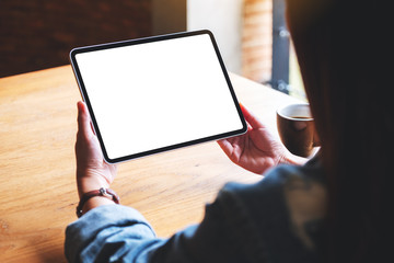 Mockup image of a woman holding digital tablet with blank white desktop screen in cafe