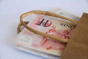 Singapore dollars in a brown paper bag.