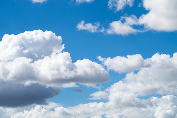 Naklejka na ściany i meble White curly clouds on the blue sky.