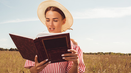 Portrait beautiful girl reading a book in the field