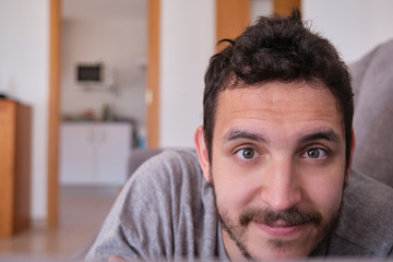 Portrait of a young caucasian handsome man lying on a sofa at home. Domestic life concept.