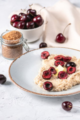 Fresh oatmeal with cherry and butter on light background
