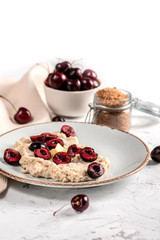 Fresh oatmeal with cherry and butter on light background
