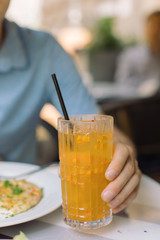 Man drinking sea buckthorn lemonade on summer terrace. Close up.