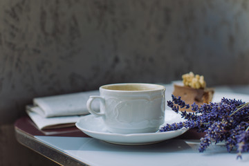 Obraz na płótnie Canvas Cup of coffee, dessert, lavender bouquet, fresh newspaper on table. Romantic coffee break on summer terrace.