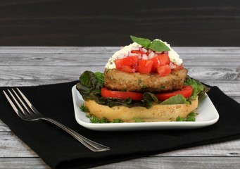 Open turkey burger garnished with chopped tomatoes, sauce, onions and basil.