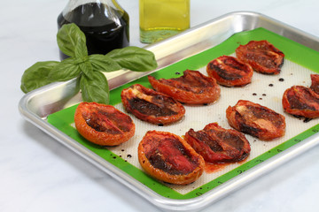 Roasted Plum tomatoes on a baking sheet.  Macro with selective focus on front tomatoes.