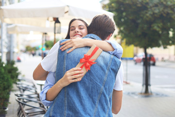 Image of attractive woman with present box giving hug to her man.
