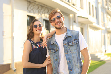 Beautiful young couple in love walking outdoors at the city street, hugging.