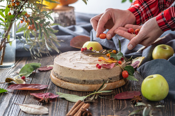 Woman is decorating a brown mousse cake with berries. Concept of autumn atmosphere and mood