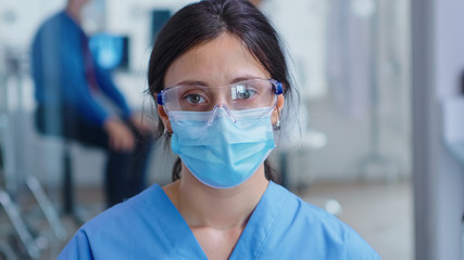 Close up of tired nurse with protection mask for coronavirus outbreak in hospital waiting room. Patient with doctor in hospital examination room.