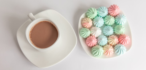 Multicolored meringues and a cup of coffee on a white background. isolated. panorama, panoramic - obrazy, fototapety, plakaty