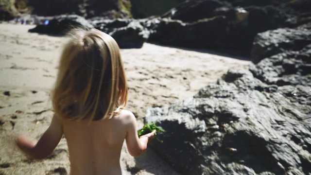 Preschooler playing near rocks on the beach