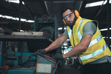 Portrait of professional technician engineer control machine in factory. He is a young businessman and owns a large turning mill.