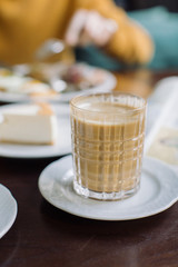 Cup of cappuccino and delicious breakfast on background at cafe on sunny day.