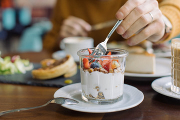 Man trying homemade granola, yogurt and fresh berries.
