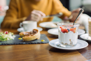 Healthy eating concept. Homemade granola with yogurt, fresh blueberries and strawberry served for breakfast with cup of cappuccino.