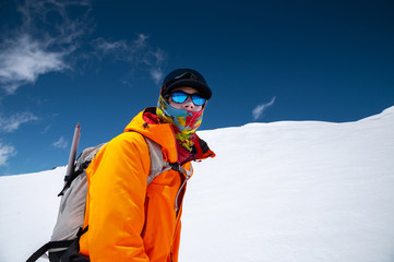 Portrait of a stern climber skier in sunglasses and a cap with a ski mask on his face. against the backdrop of Mount Elbrus