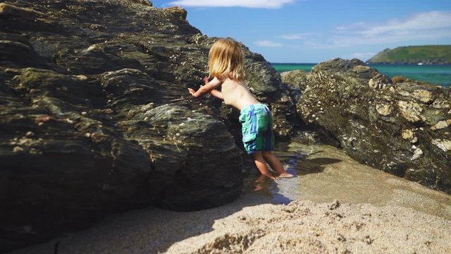 Preschooler playing near rocks on the beach