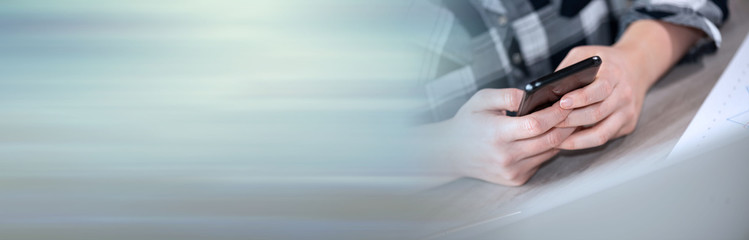 Female hands using a smartphone; panoramic banner