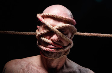 Image of binded adult man with rope on face
