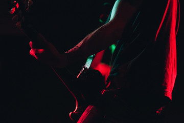Rock guitarist performing on stage - vibrant stage red and green lights