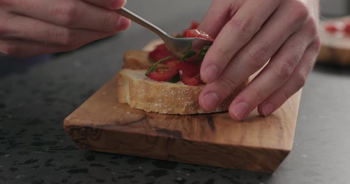 Slow motion making bruschetta with cherry tomatoes and spinach leaves