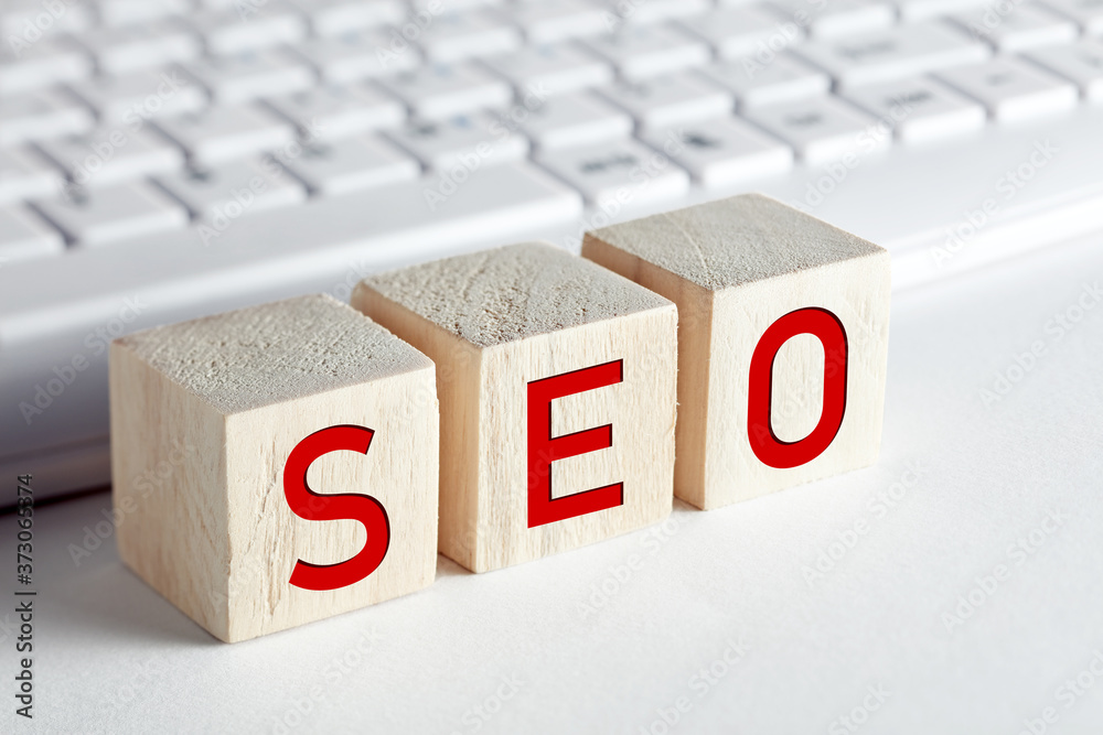 Fototapete the word seo (search engine optimization) written on wooden blocks with computer keyboard background