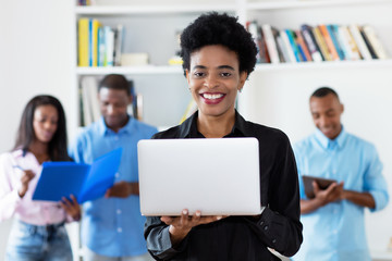 Laughing african american businesswoman at computer with group of black business people