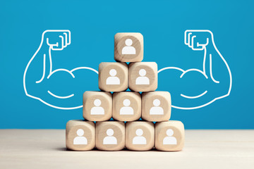 Wooden blocks stacked as pyramid hierarchy with people icons. Power of teamwork, solidarity or...