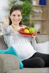 woman holds fruits on bowl while showing thumb up