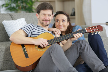 couple on sofa and playing on acoustic guitar